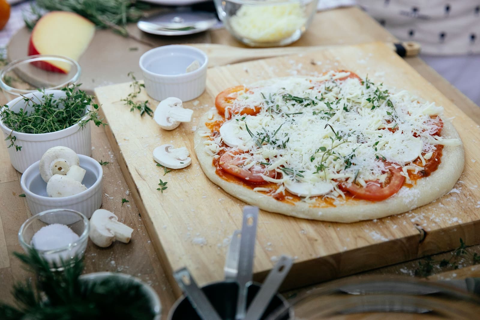 A stretched pizza base resting on a floured board in a bright kitchen