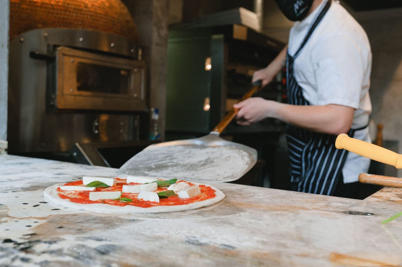 A raw pizza resting on a floured wooden peel